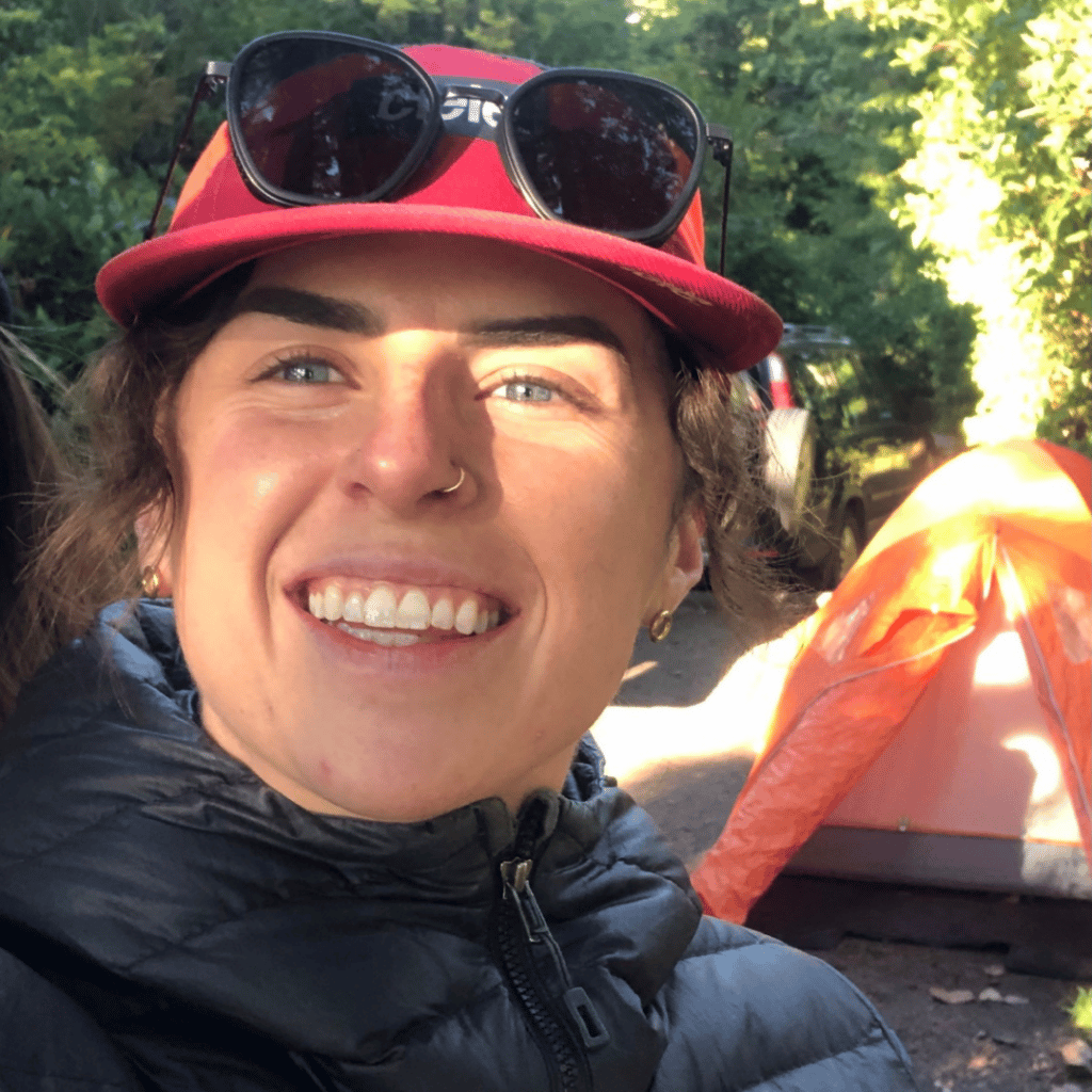 Smiling woman standing in front of tent campsite